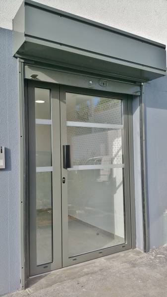 Porte d'entrée en aluminium gris installée dans l'entrée d'un immeuble